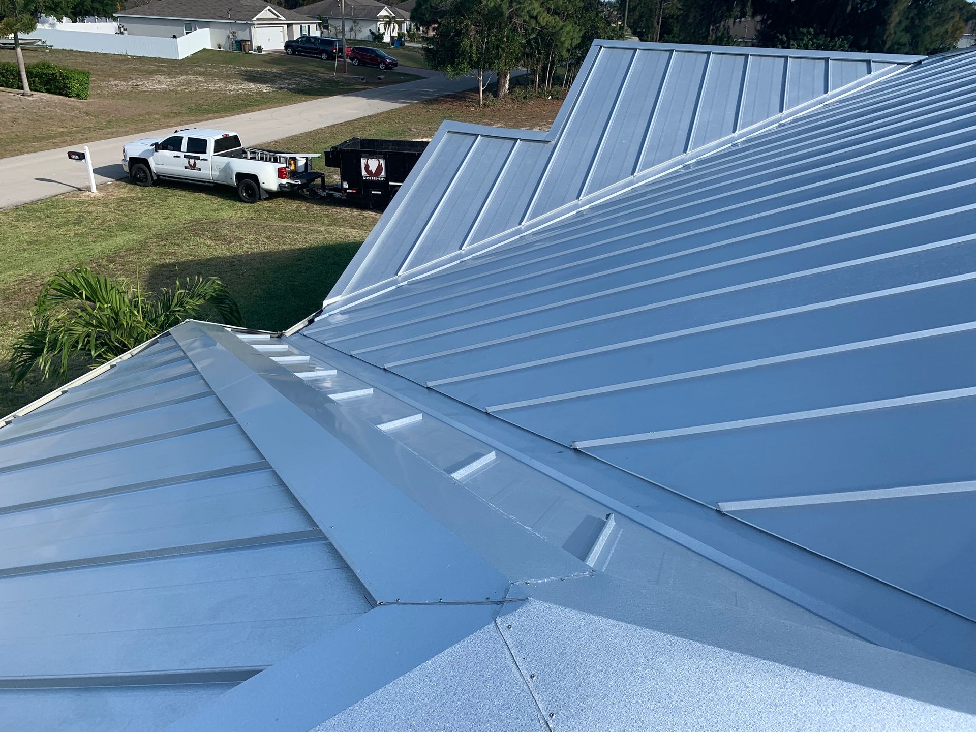 Blue metal roof with a row of standing seams, viewed from above on a sunny day.