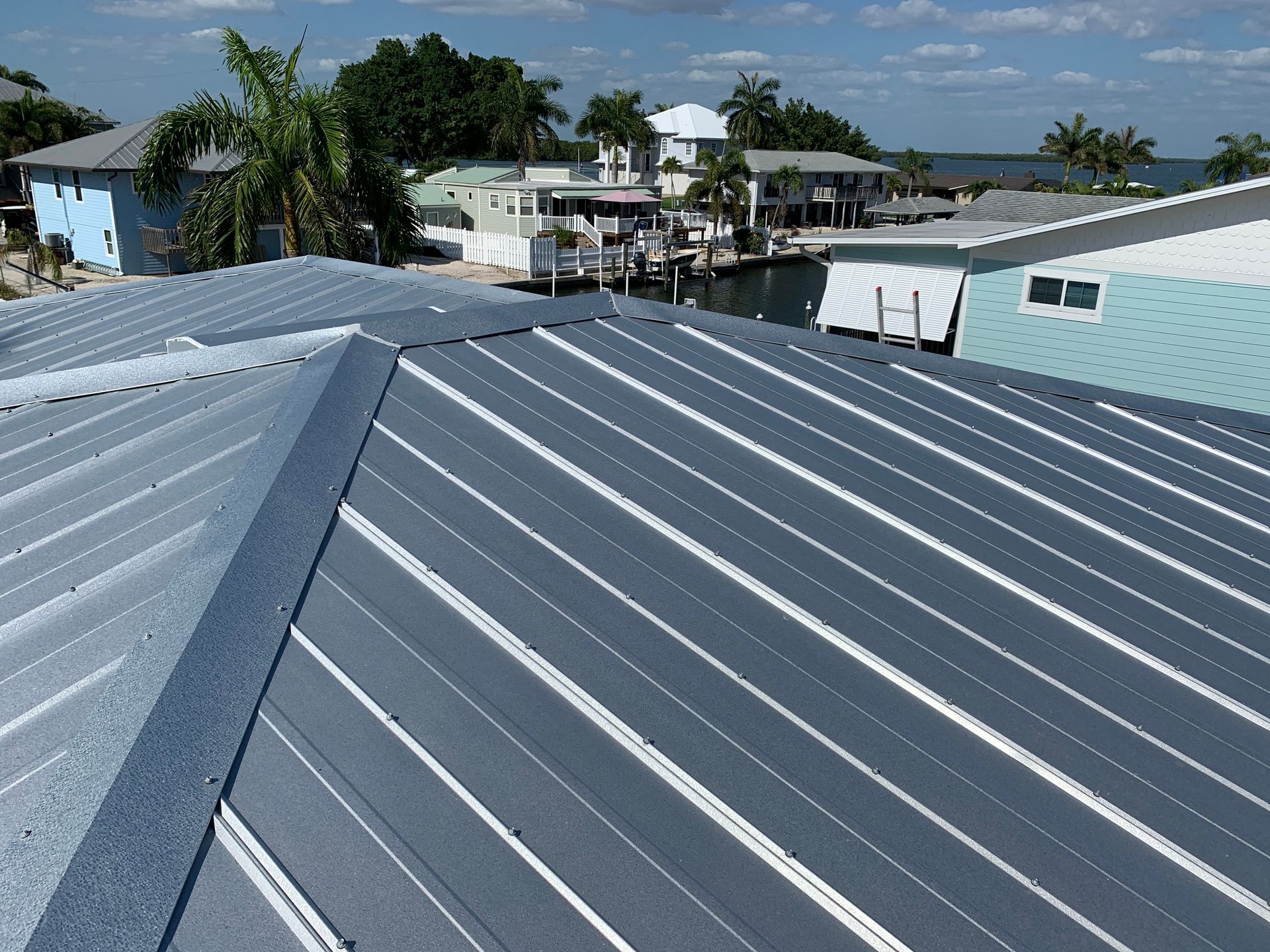 Gray metal rooftop with standing seams in a sunny coastal neighborhood