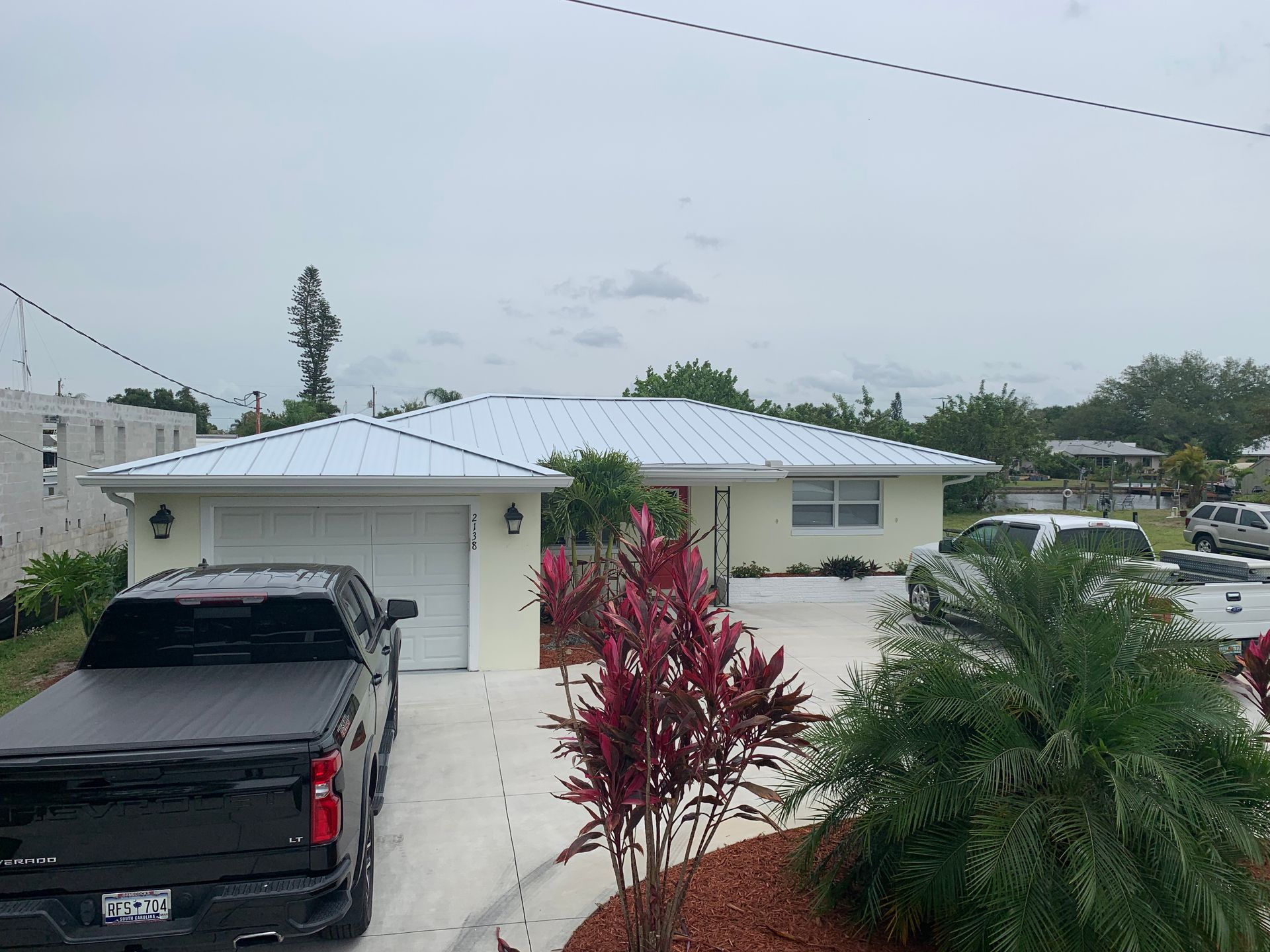 Single-story house with a black pickup in the driveway and palm trees in the front yard