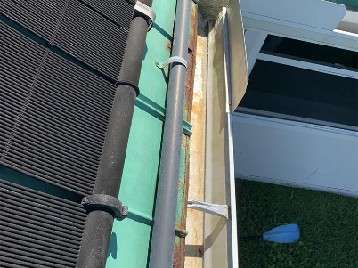Close-up of a green wall and metal railing beside black mesh fencing and artificial grass below