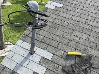 Roof vent pipe on shingled roof with a coiled black cable and yellow tool nearby