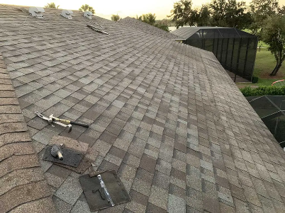 Damaged roof exposed under a blue tarp, with torn shingles and missing sections