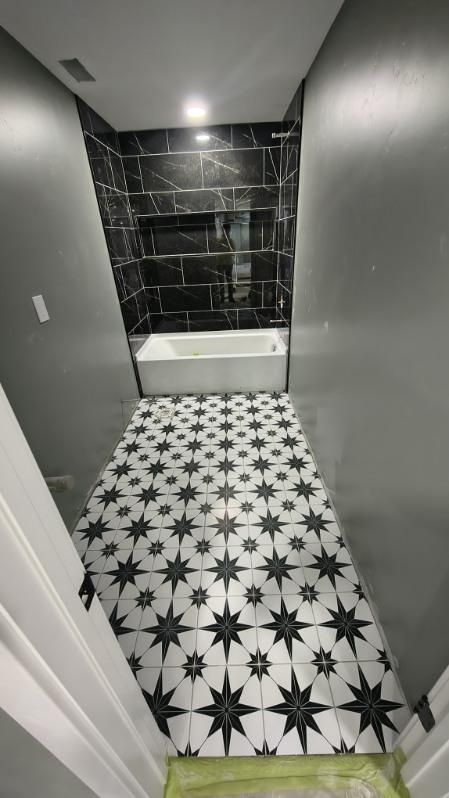 Narrow bathroom with black-and-white star tile floor and dark tiled shower wall