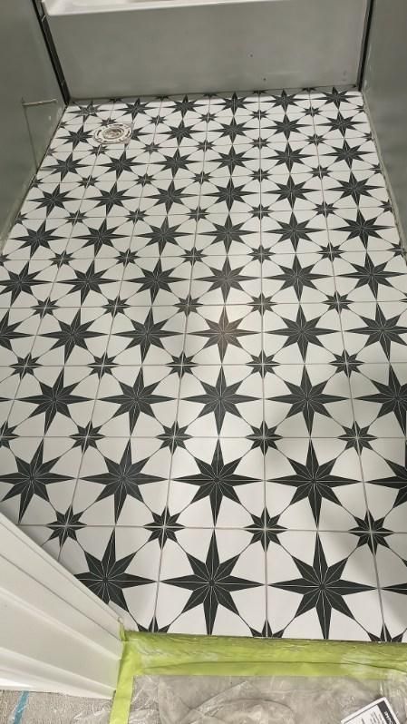 Black-and-white star-patterned tile floor in a doorway, with tape along the bottom edge and gray wall beyond