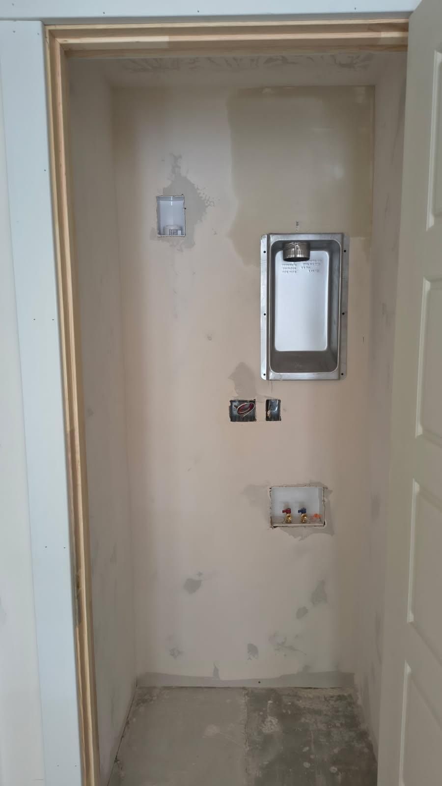 Small unfinished wall niche with electrical outlets and a metal panel, in a construction area