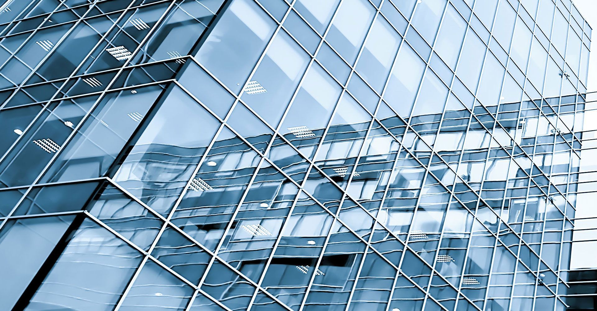 Modern glass skyscraper reflecting the sky, angled view, blue hues.