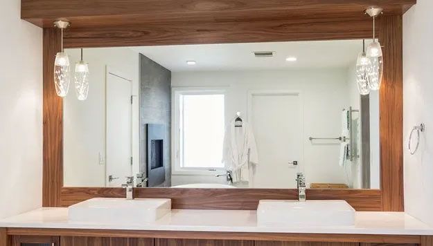 Bathroom with large mirror, two sinks, decorative lights, and a window.