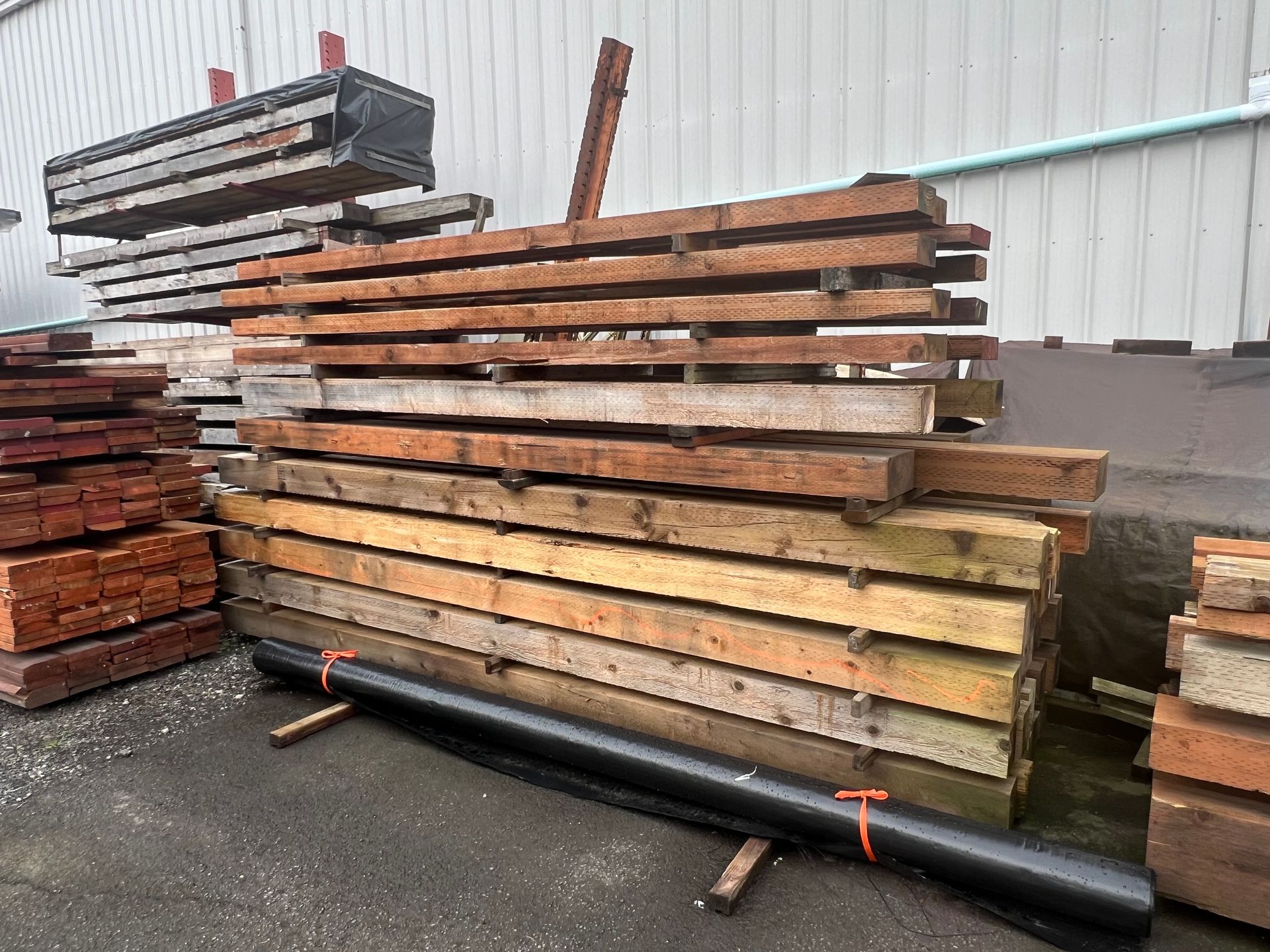 A pile of wood is sitting on the ground in front of a building.