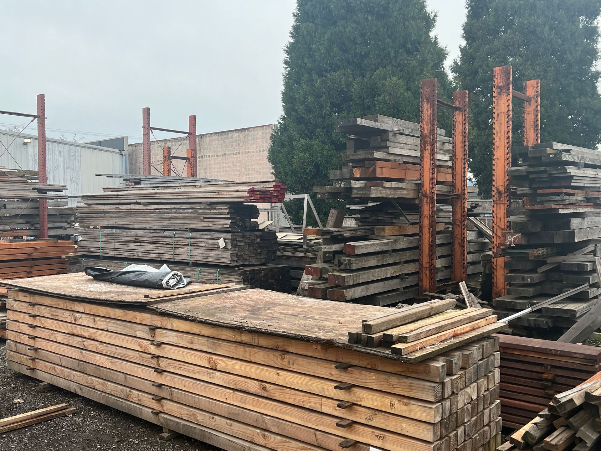 A bunch of wooden boards are stacked on top of each other in a yard.