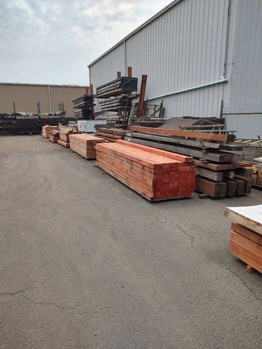 A large pile of wood is sitting in front of a building.