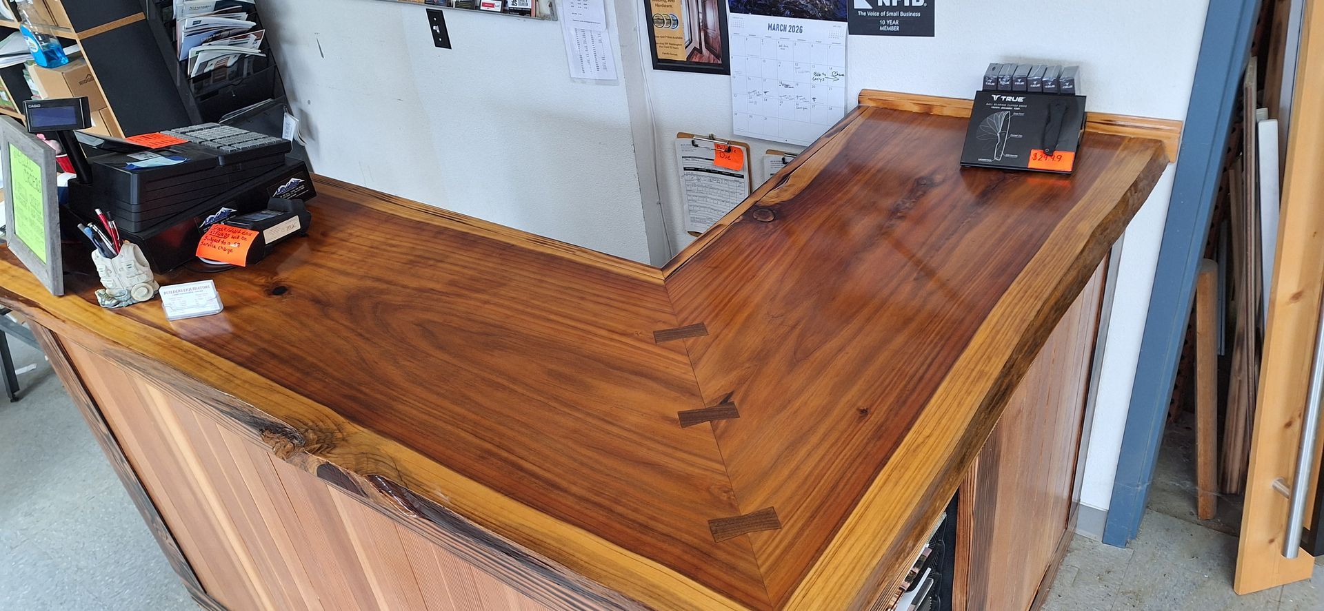 L-shaped wood counter with a live edge, featuring a dark stained surface joined by butterfly inlays.