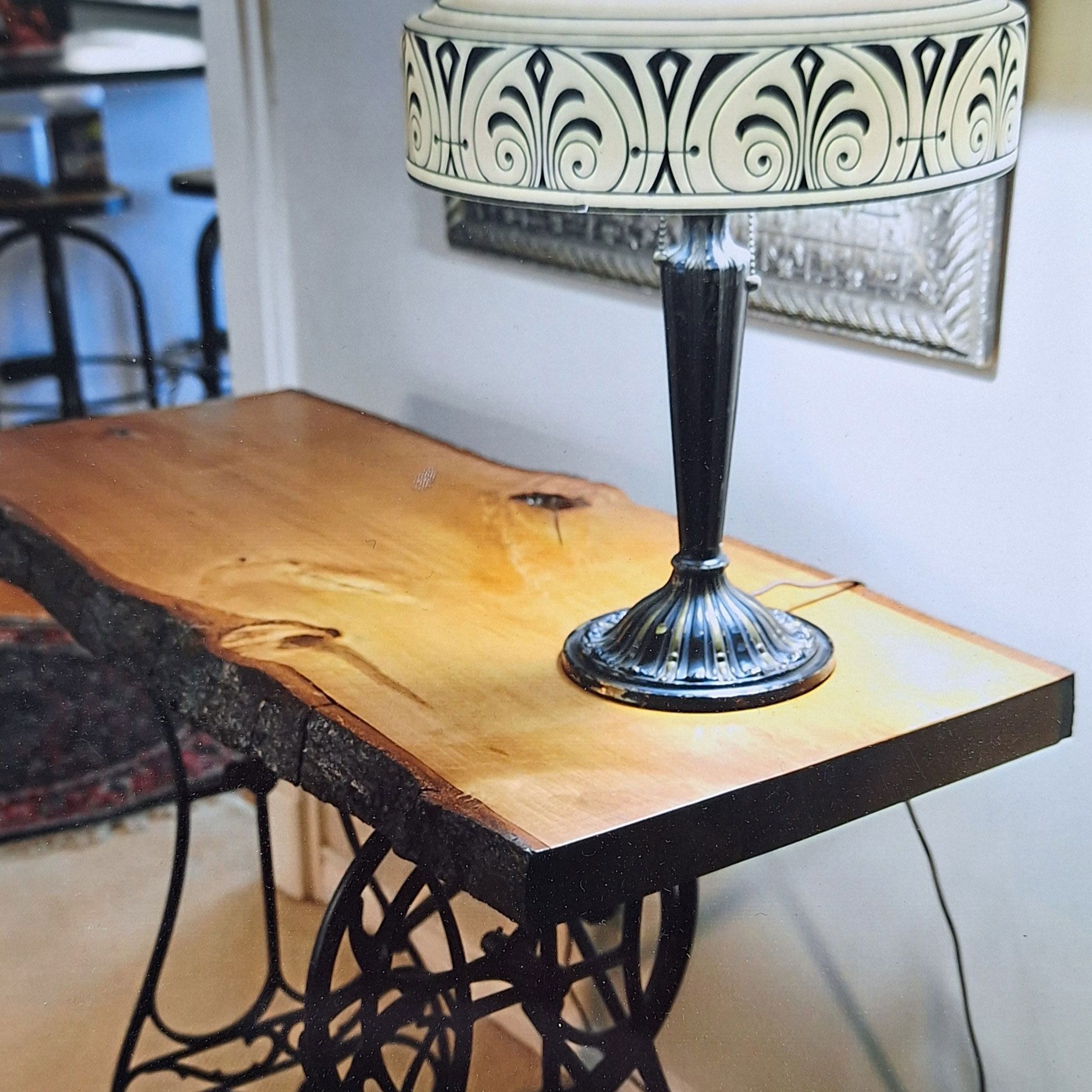 A live-edge wooden console table with a vintage sewing machine base and a decorative lamp in a home setting