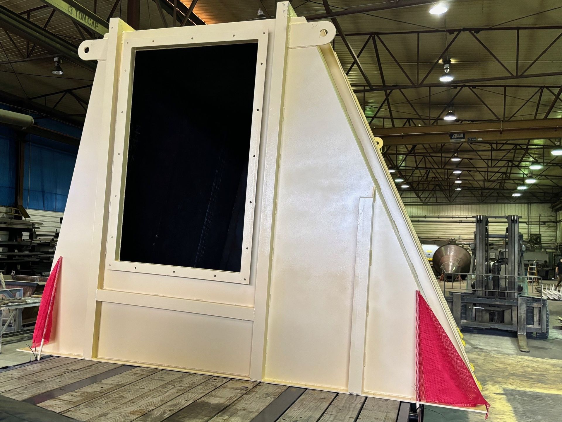 A large piece of metal is sitting on top of a wooden table in a factory.