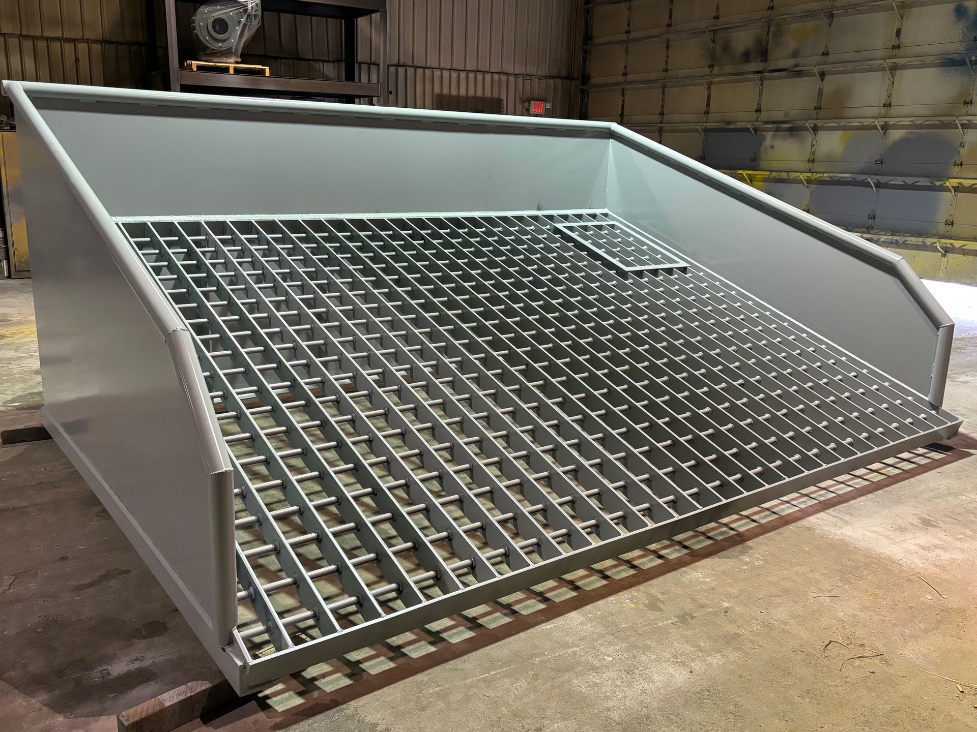 A metal grate is sitting on top of a concrete floor.