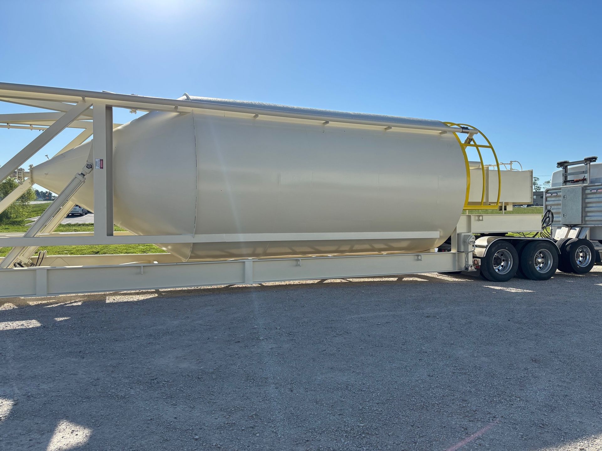 A large white truck is parked in a gravel lot.