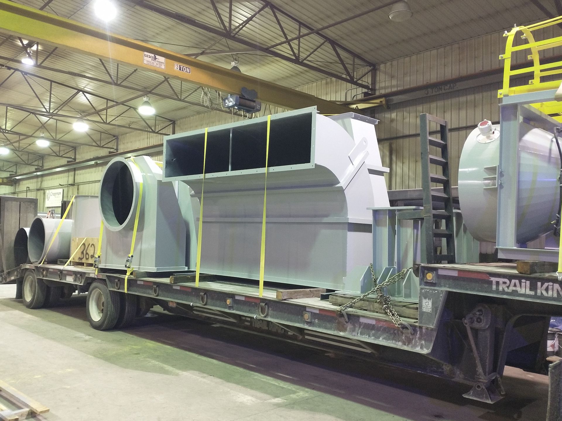 A trail king semi truck is carrying a large piece of metal.