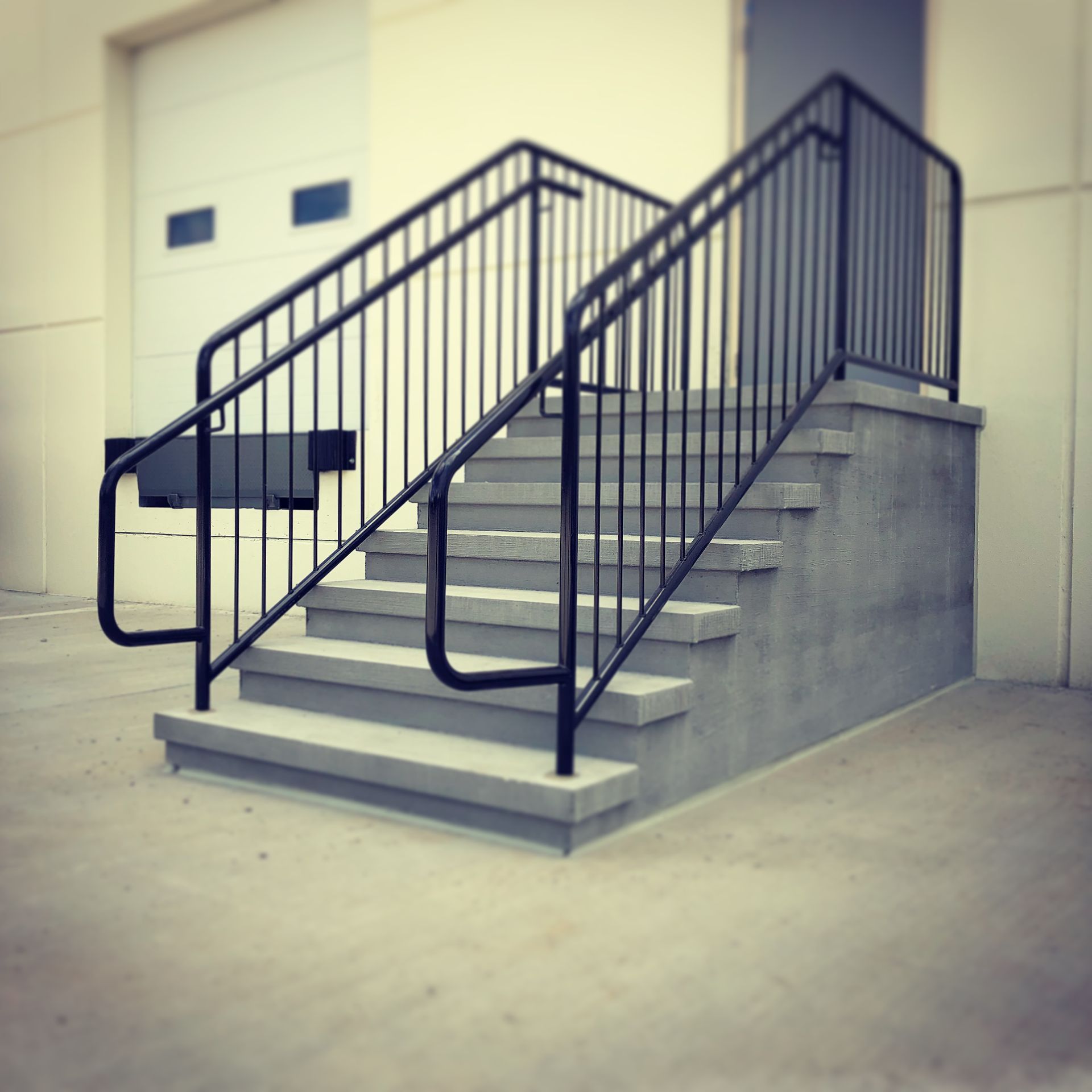 A set of concrete stairs with a black railing