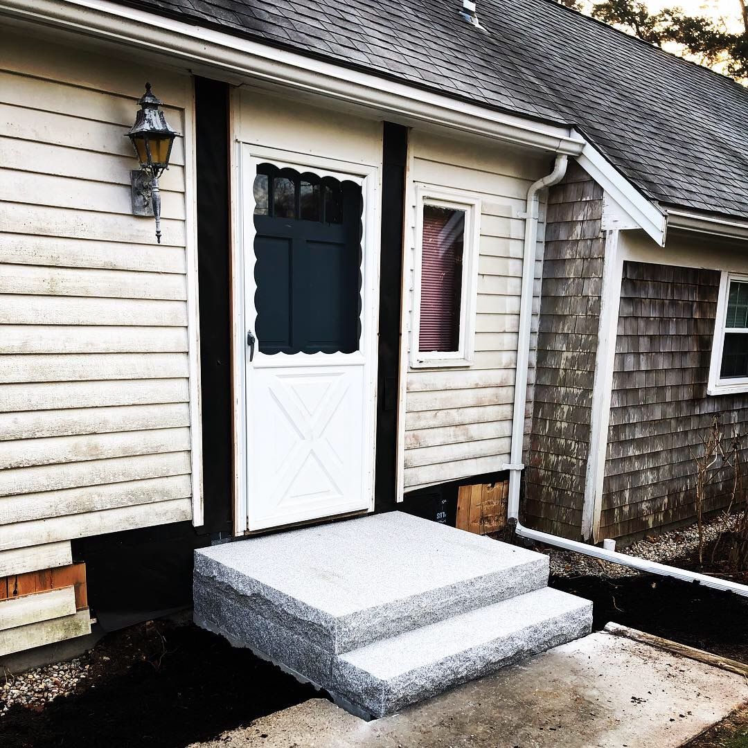 A white house with a black door and steps