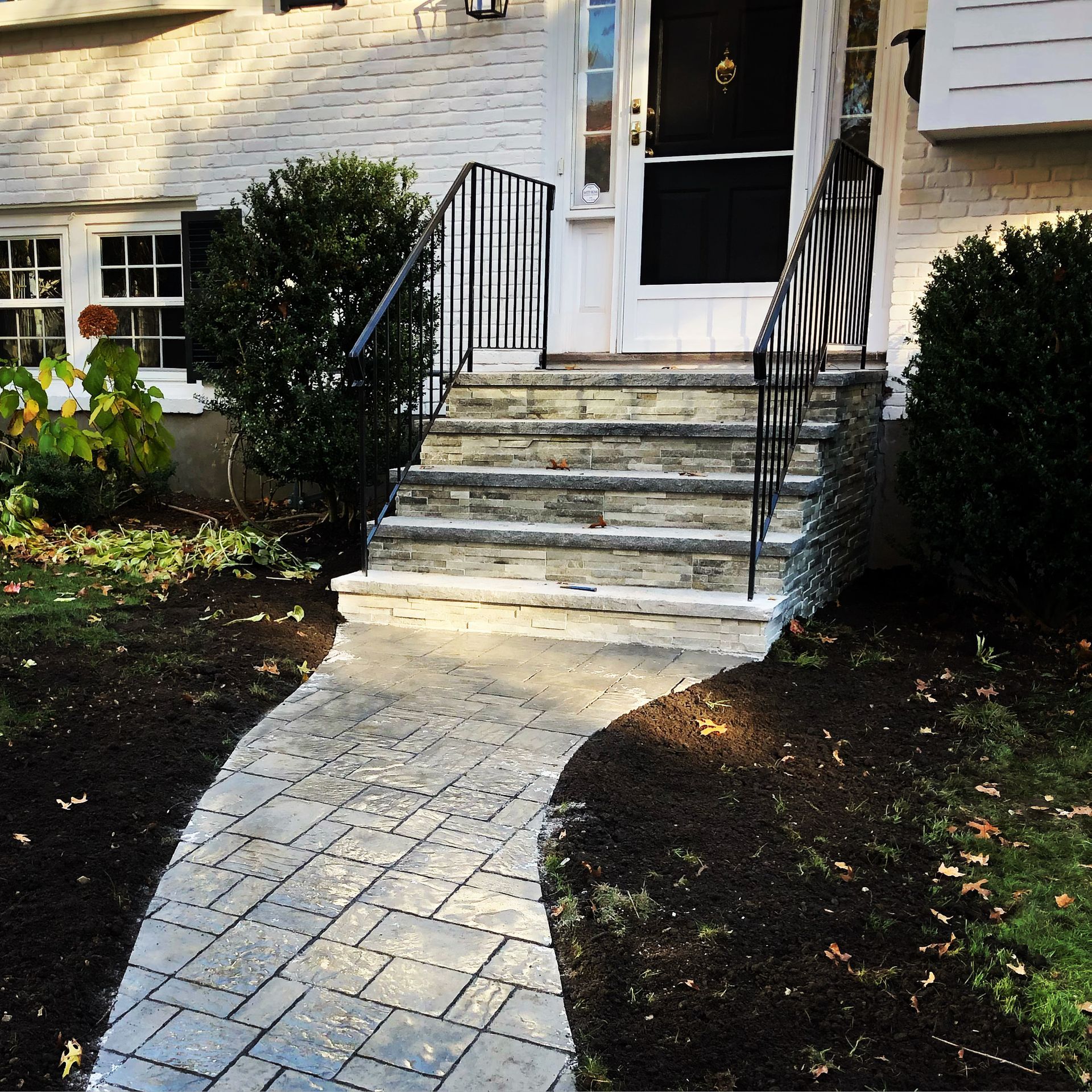 A stone walkway leads to the front door of a house