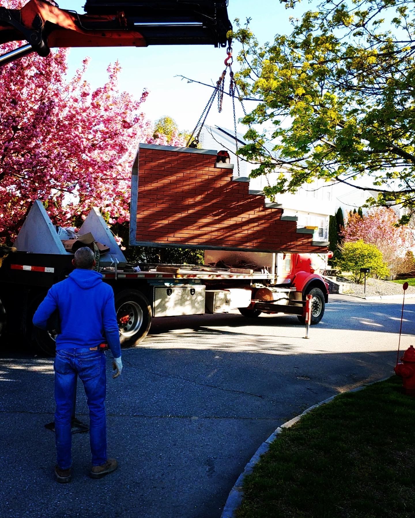 A man in a blue jacket is standing next to a truck with stairs on it