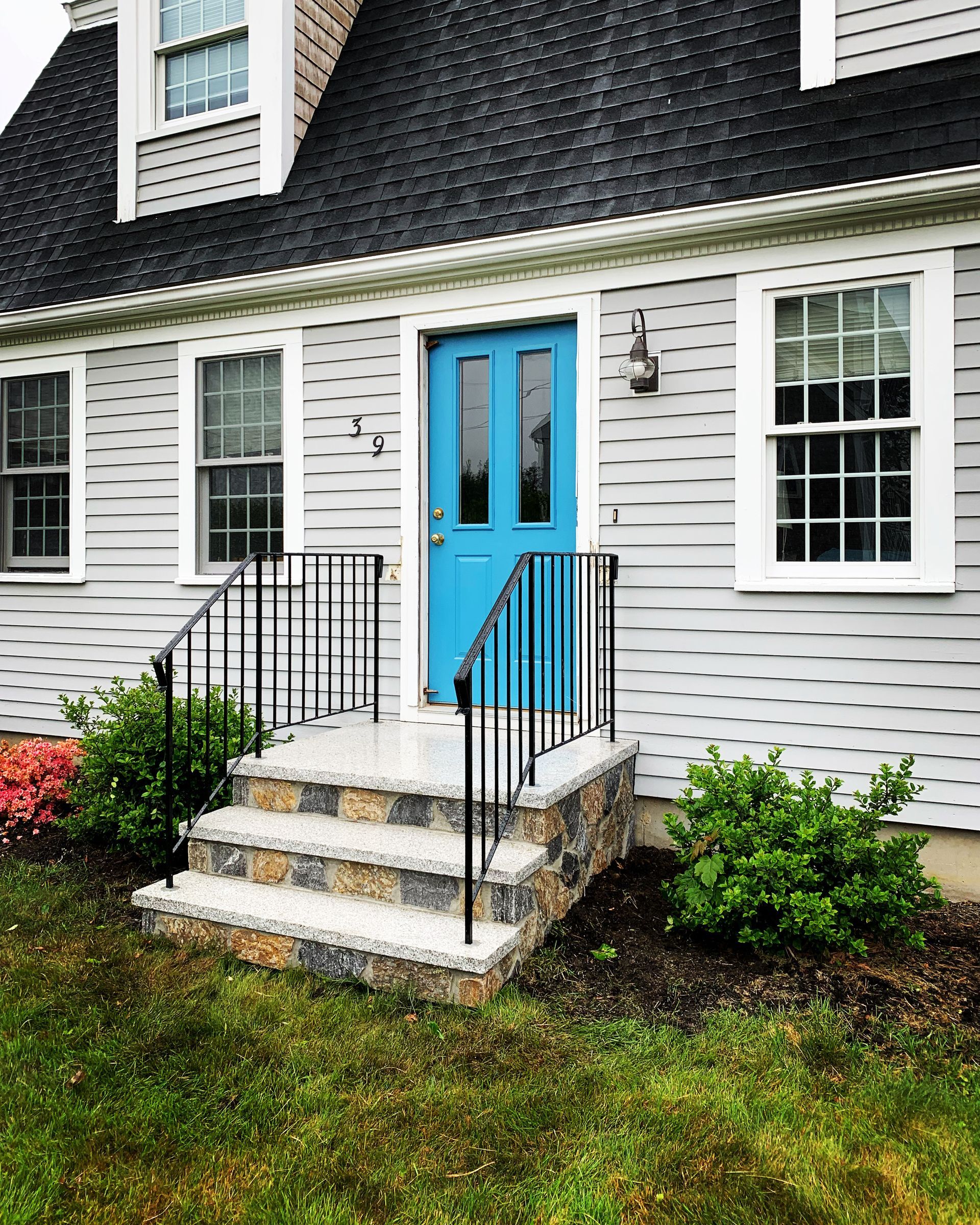A white house with a blue door and stairs