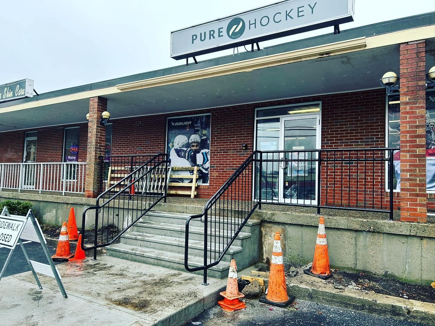 A brick building with stairs and a sign that says pure hockey.