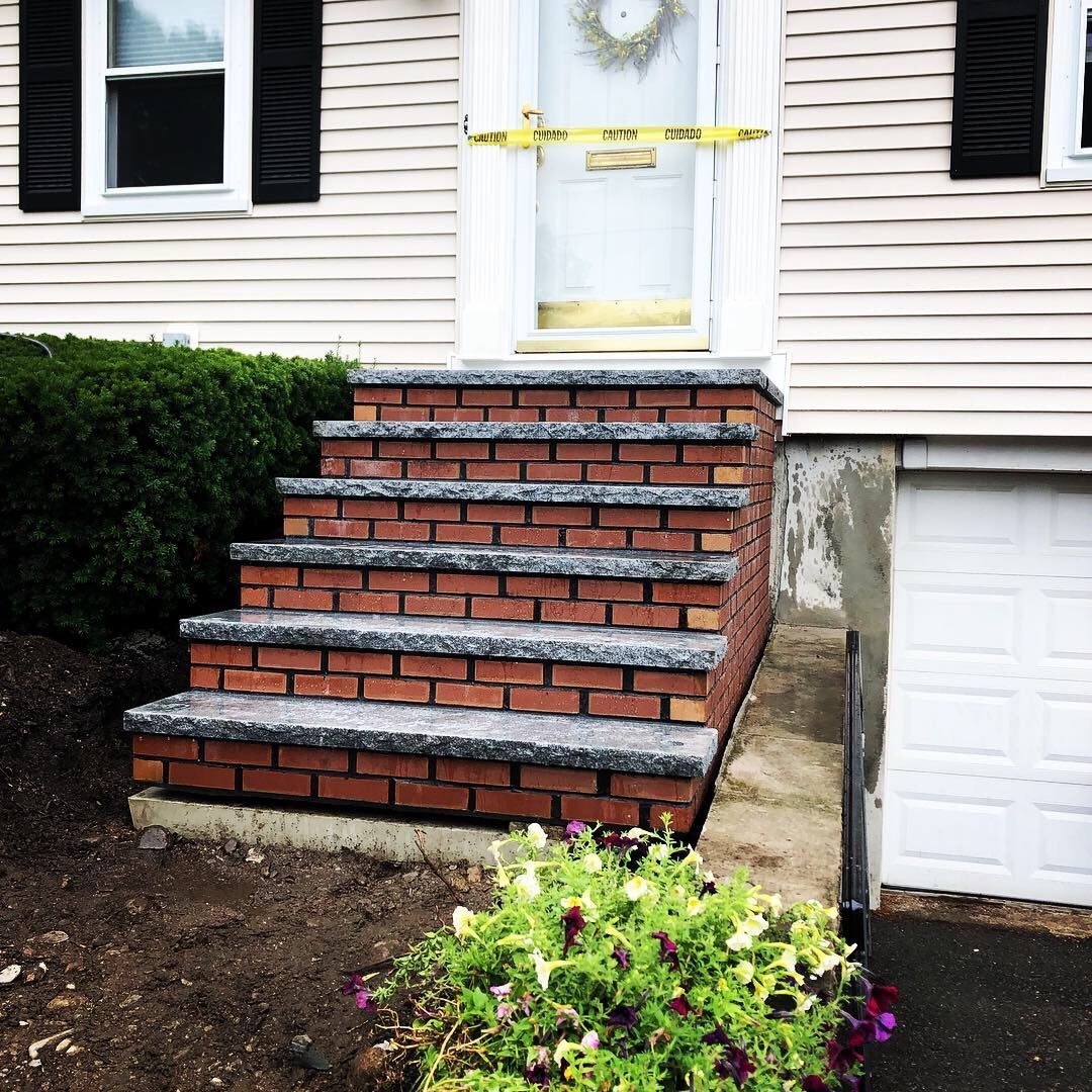 A white house with brick steps leading up to the front door