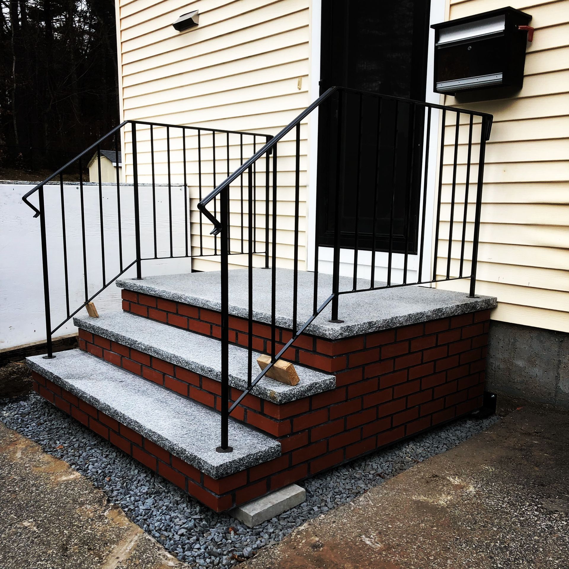 A brick porch with stairs and a wrought iron railing