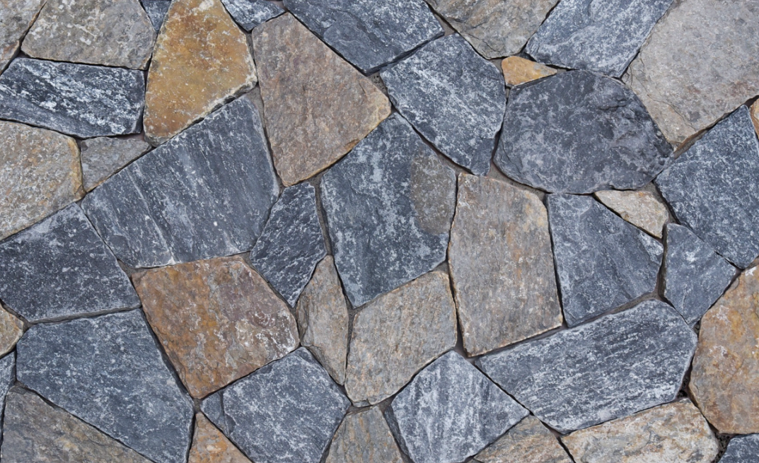 A close up of a stone wall made of different colored rocks.