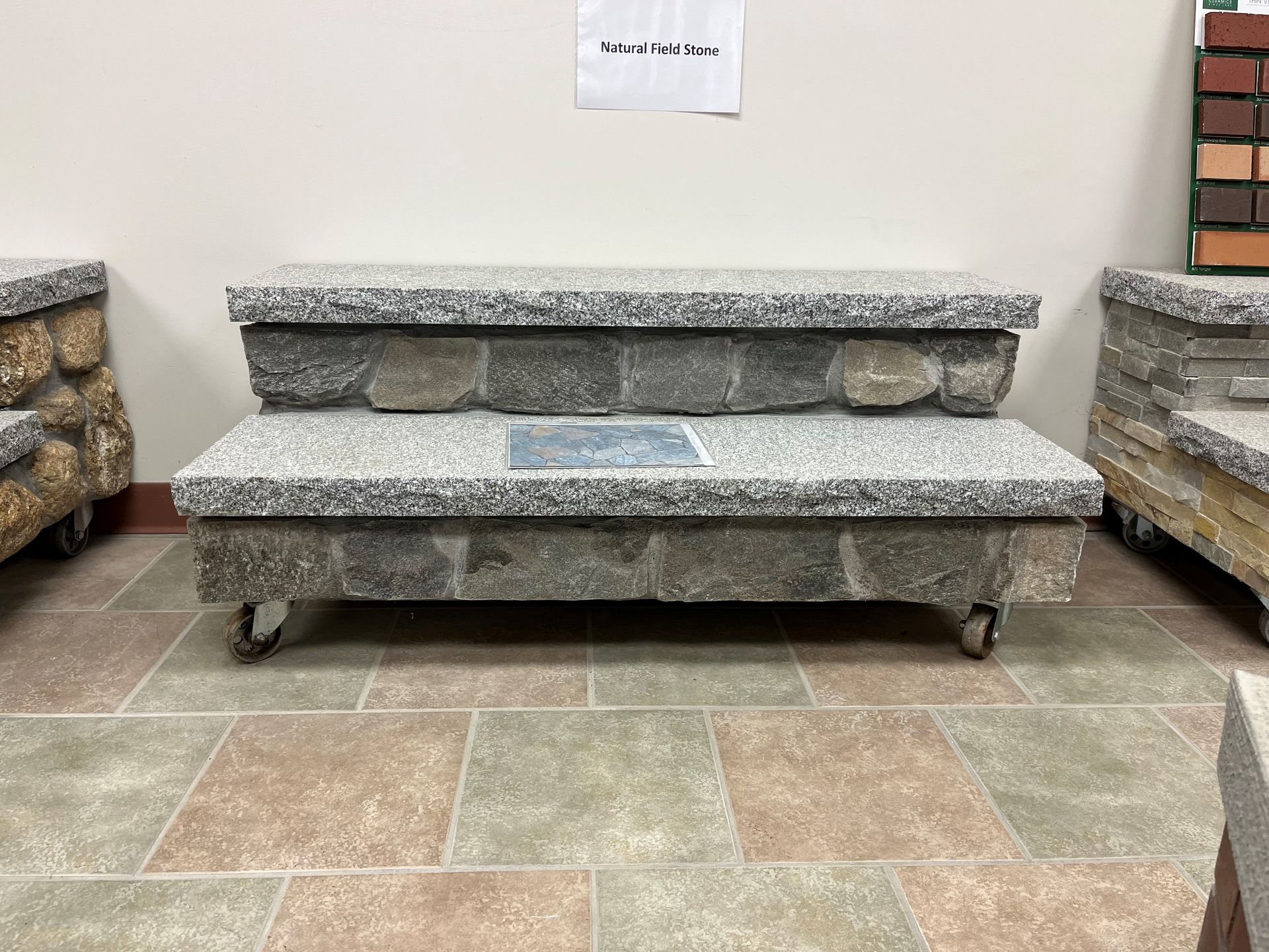 A stone bench with wheels is sitting on a tiled floor in a room.