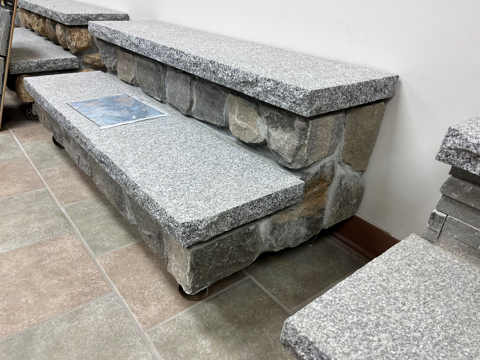 A stone bench is sitting on top of a tiled floor.