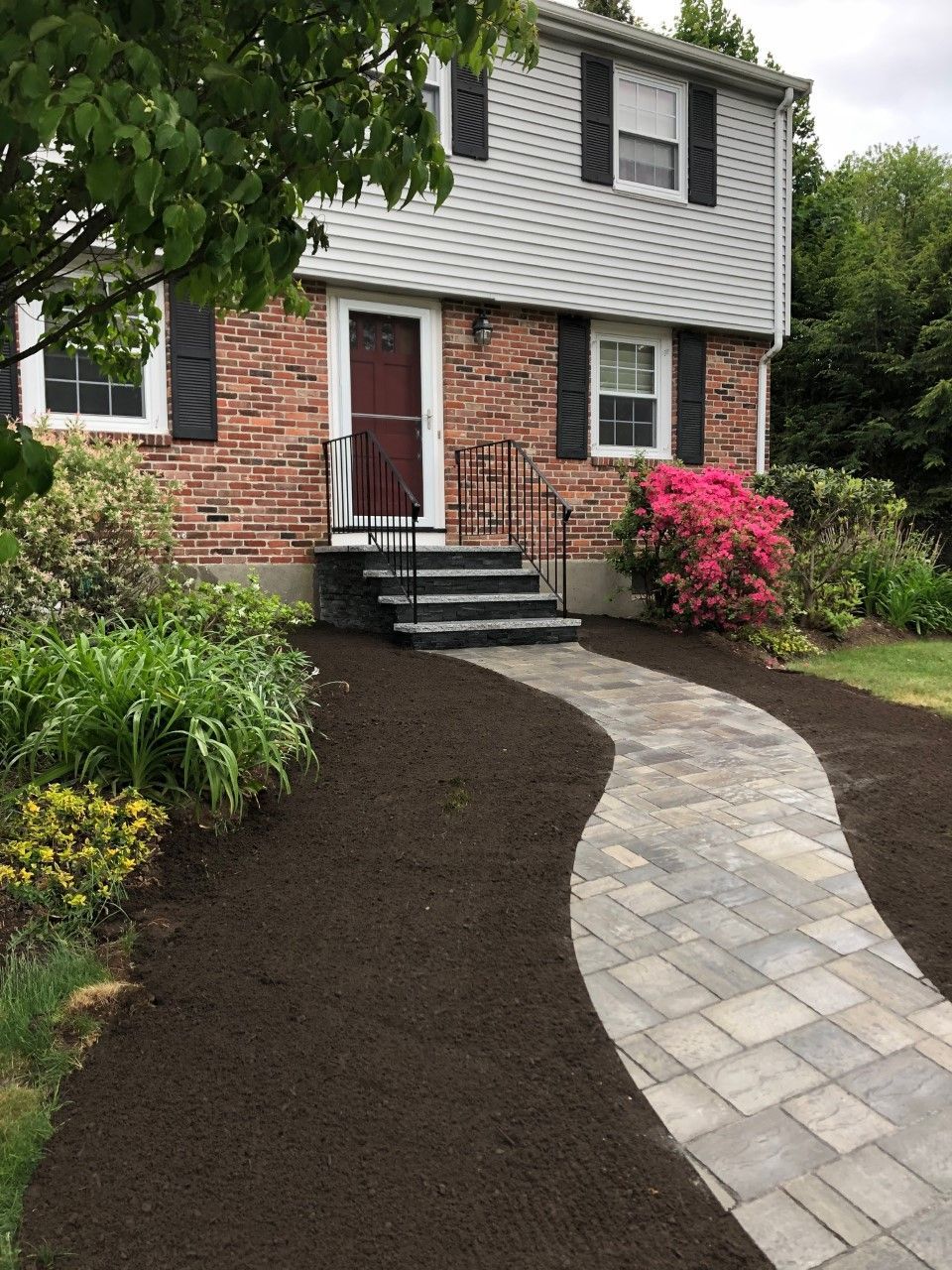 A brick house with a walkway leading to the front door