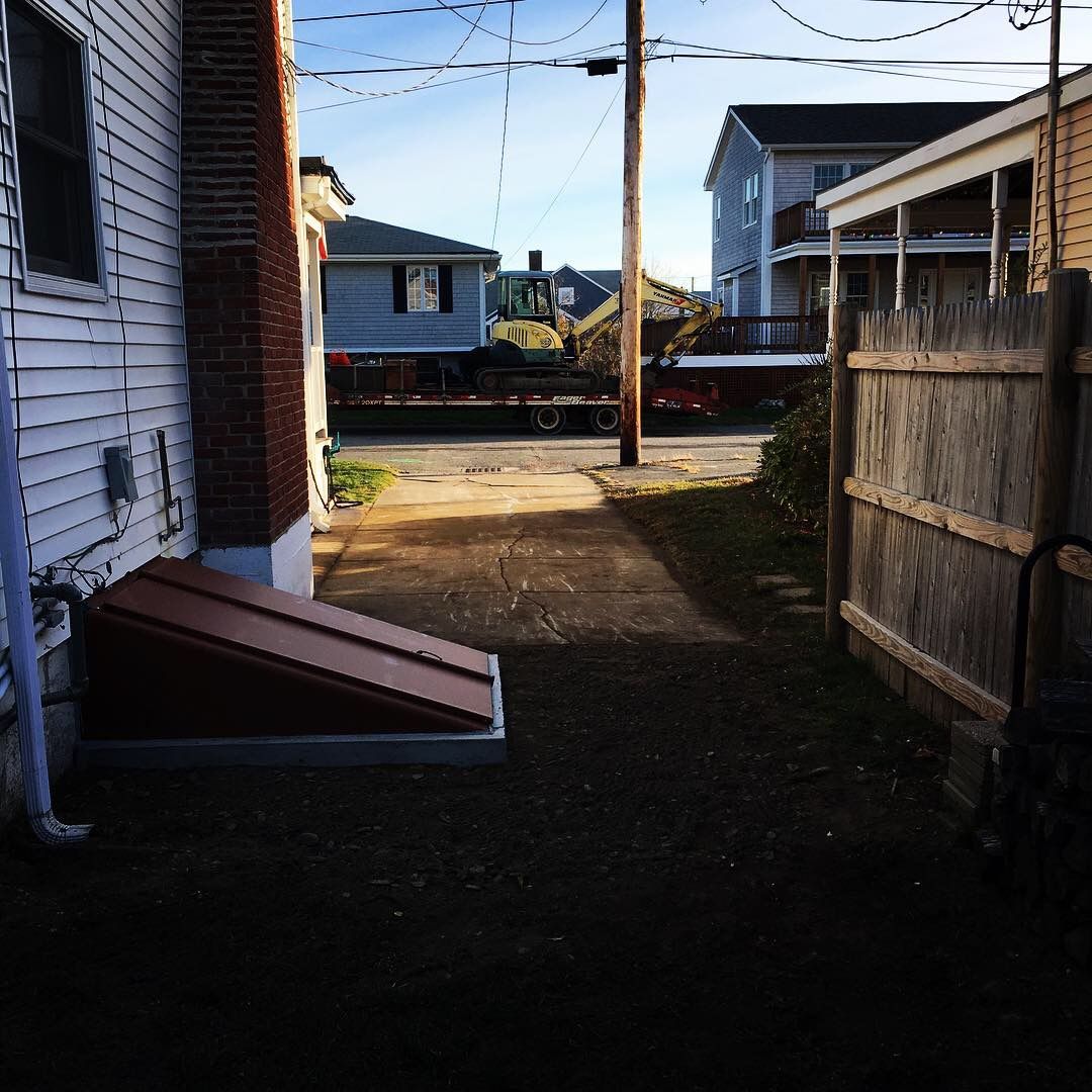 A backyard with a wooden fence and a tractor in the background