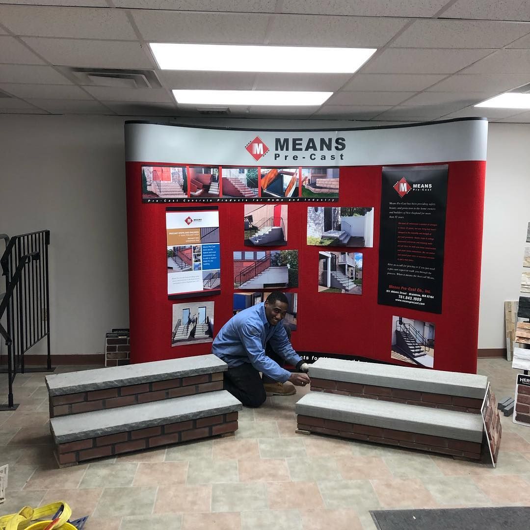 A man is kneeling in front of a wall that says means