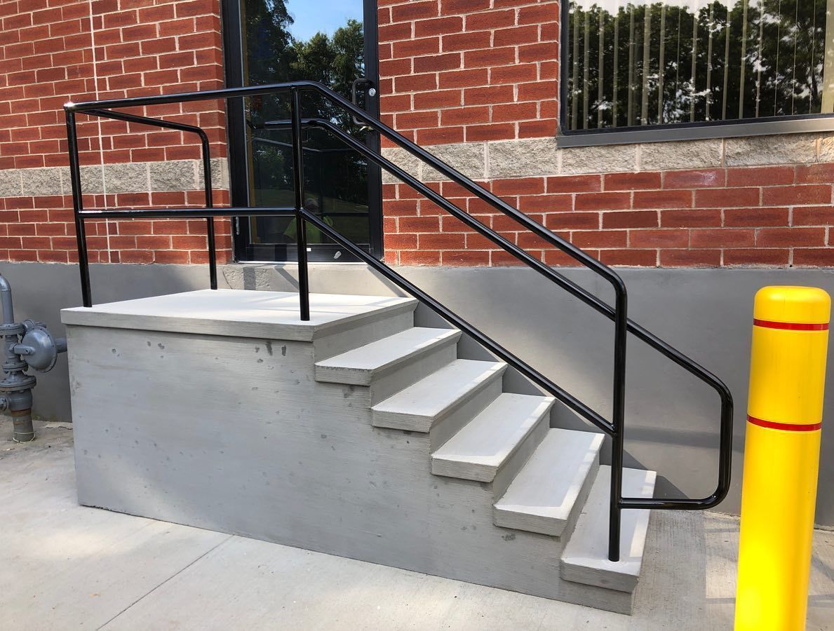 A set of stairs leading up to a brick building with a metal railing