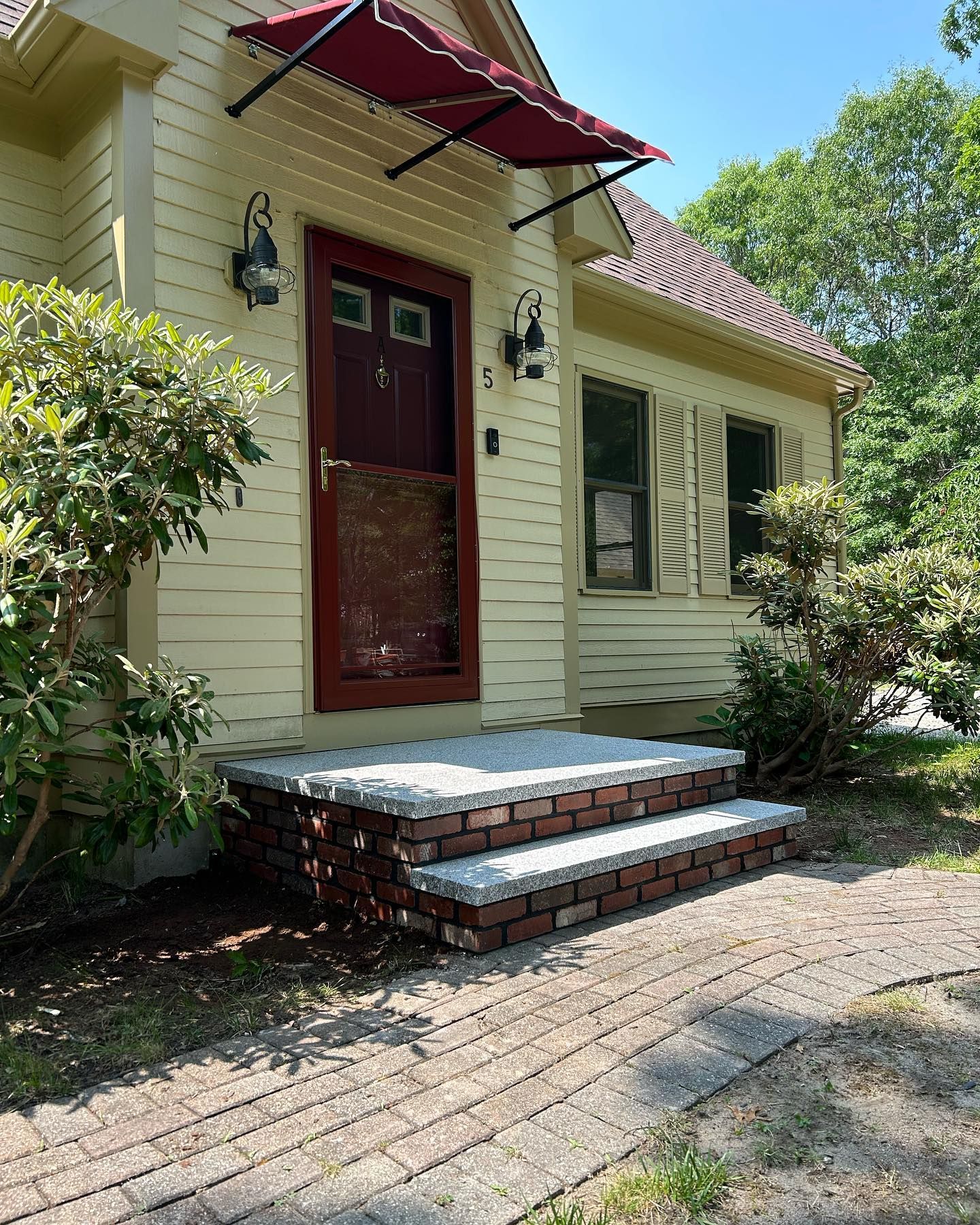 A house with a red awning over the front door and steps.