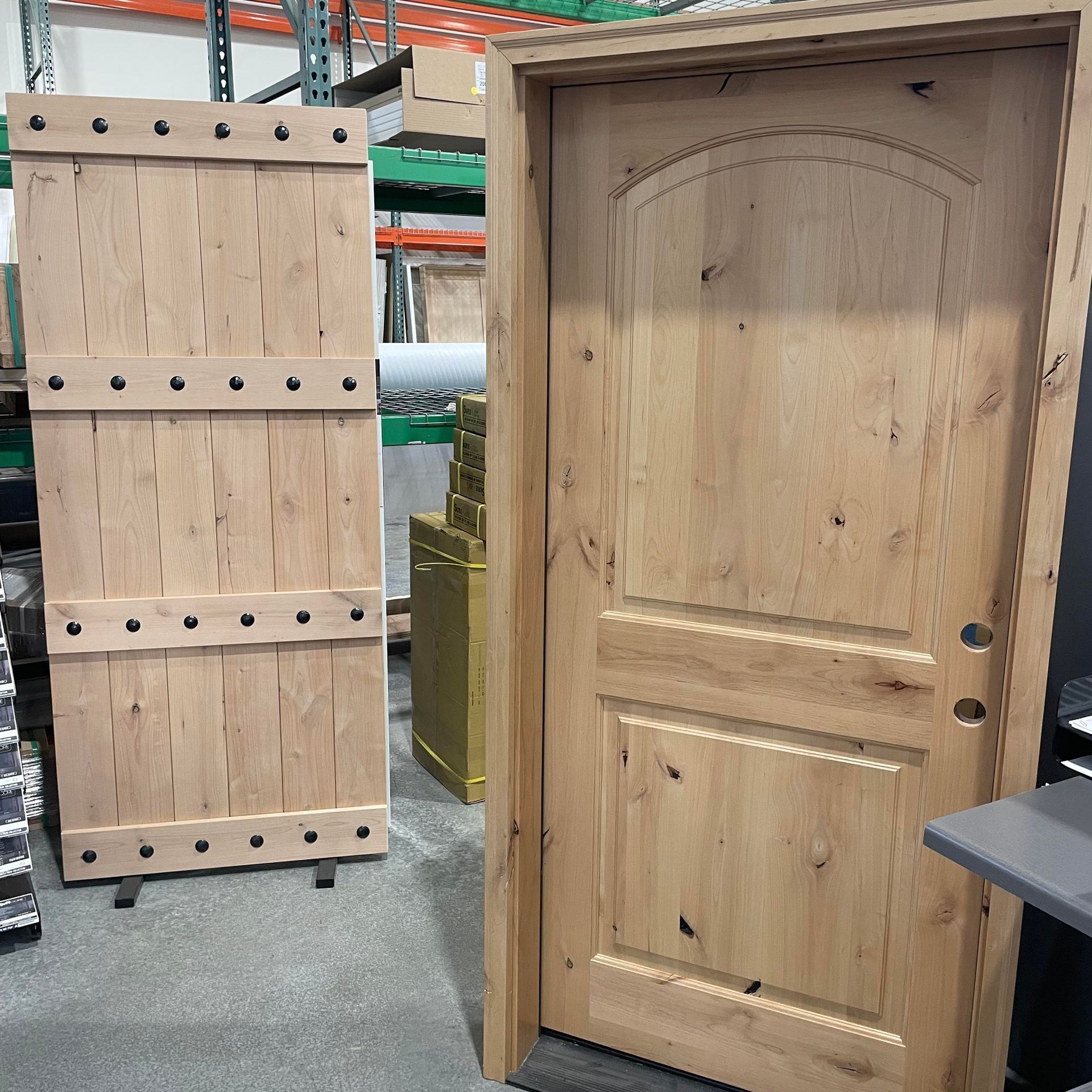 Two light-colored wooden doors: one with vertical planks and rivets, the other a traditional paneled door with an arched top.
