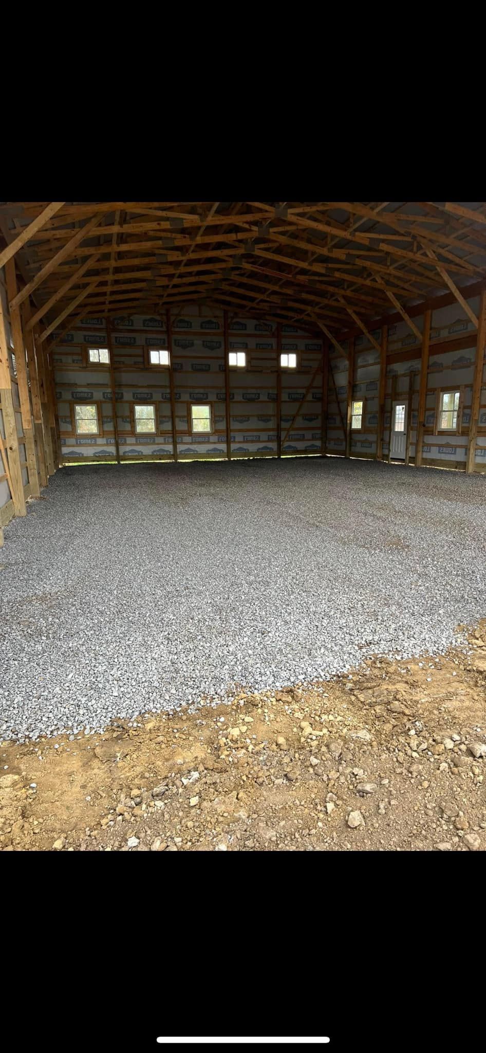 A large empty barn with gravel in the floor.