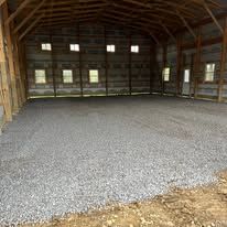 The inside of a barn with gravel on the floor.