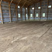 A large empty barn with a lot of dirt on the floor.