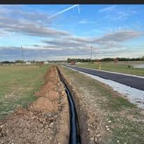 A pipe is being installed in the ground next to a road.