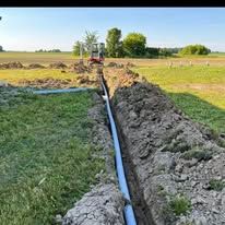 A pipe is being installed in a trench in a field.