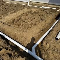 A bunch of pipes are laying in the dirt.