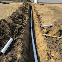 A pipe is being installed in a trench in the dirt.