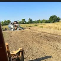 A person is sitting in a chair in a field with a playground in the background.