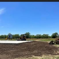 A bulldozer is sitting on top of a dirt field next to a playground.