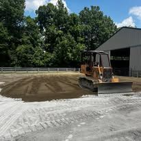 A bulldozer is working on a dirt field in front of a building.