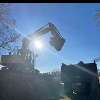 A large excavator is digging a hole in the ground next to a dump truck.