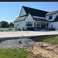 A large white house with a concrete driveway in front of it.