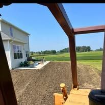 A bulldozer is moving dirt in front of a house.